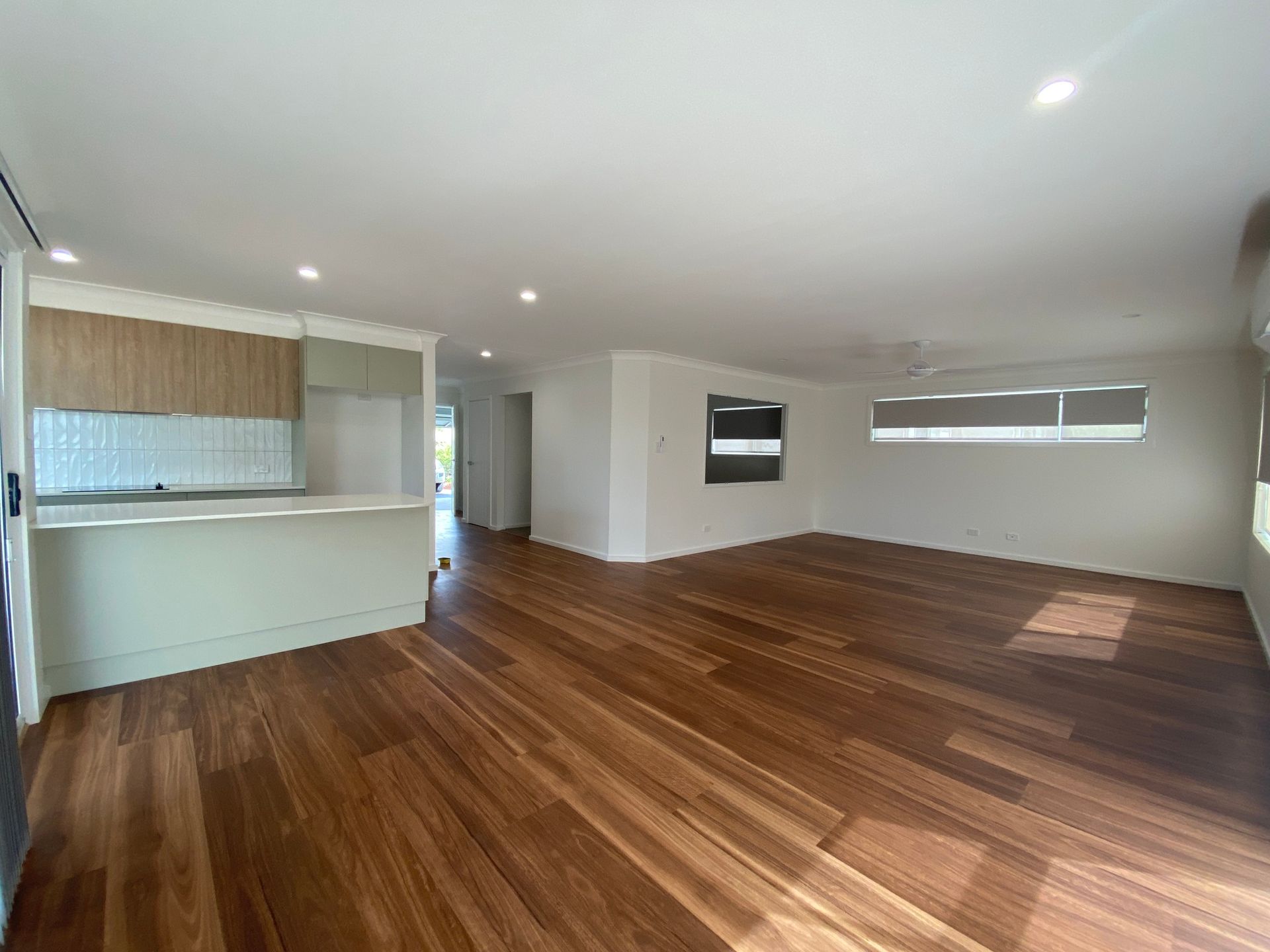 Empty Living Space With Hardwood Floors, a Kitchen Counter, and White Walls — BK Building Services Pty Ltd In Taree, NSW