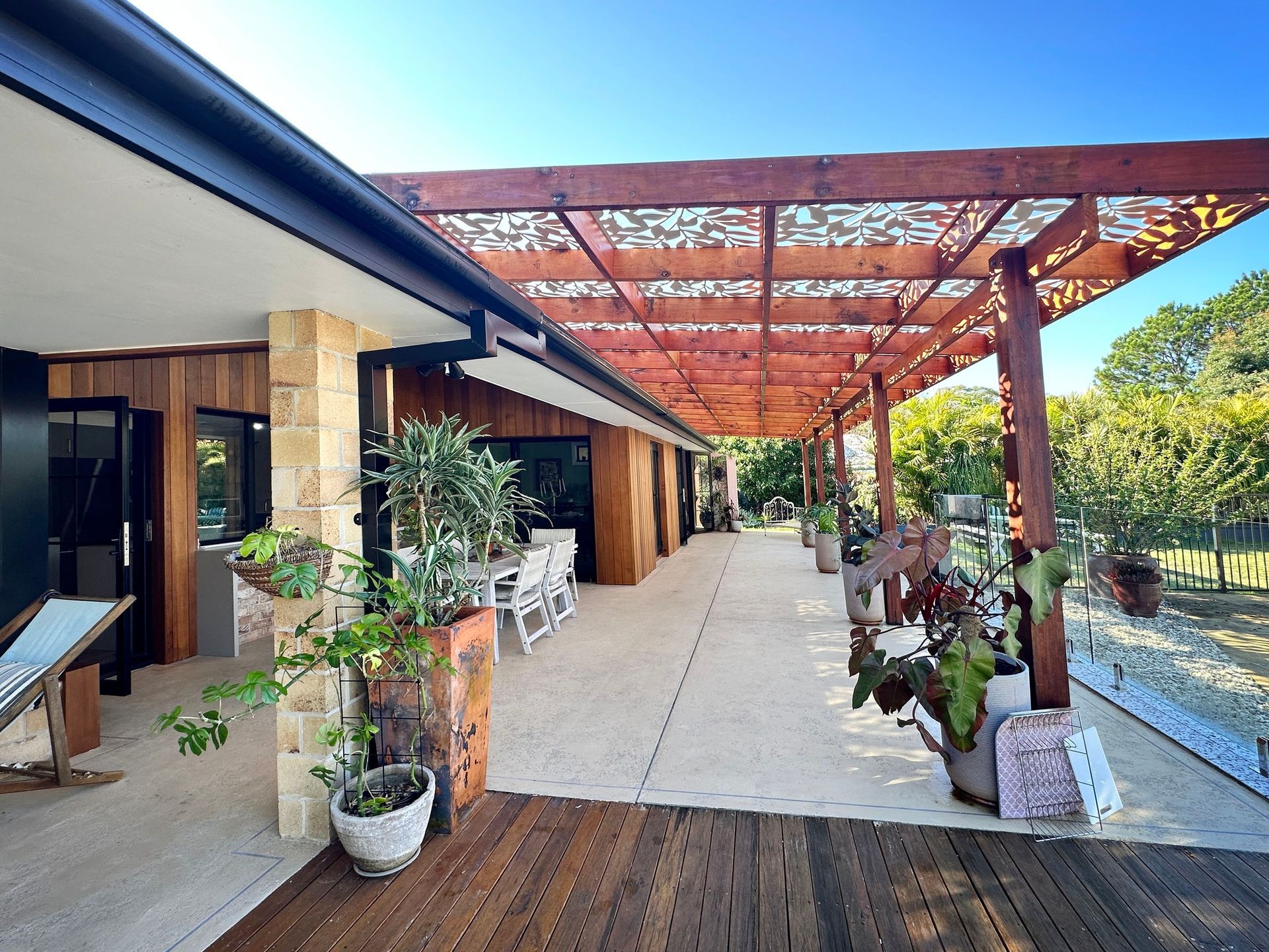 Patio With Wooden Pergola, Plants in Pots, and a House With a Wooden Facade — BK Building Services Pty Ltd In Taree, NSW