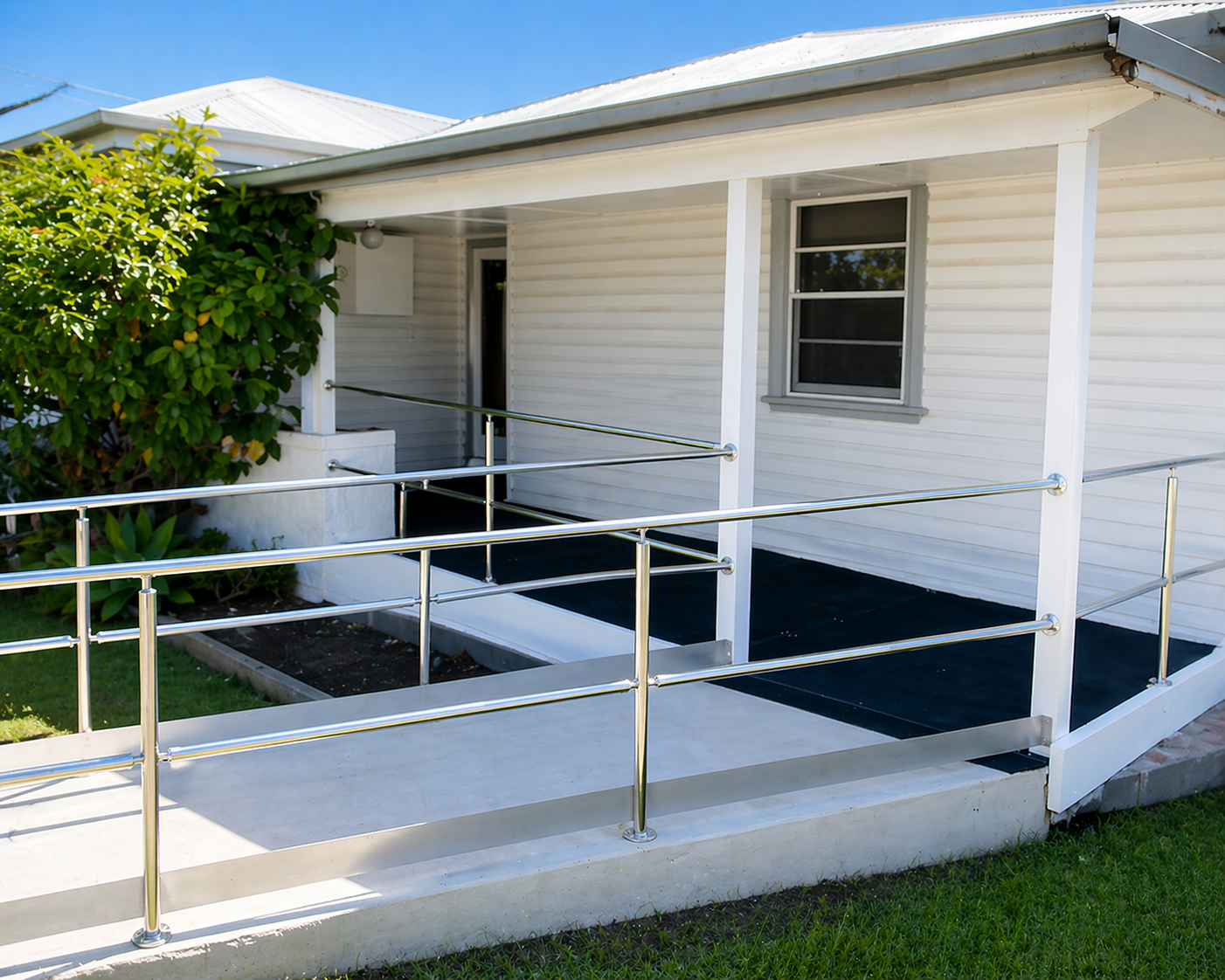 White house ramp with metal railings leading to a covered porch and windowed entrance