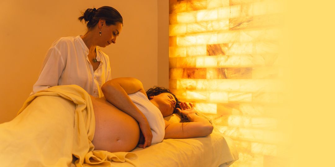Eine schwangere Frau erhält eine Massage. Ein Therapeut bearbeitet sanft 