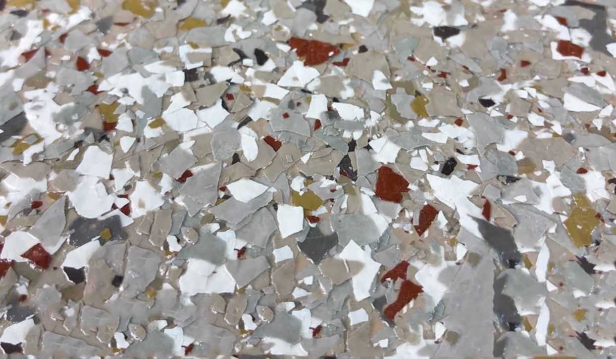 Close-up of a speckled floor coating, featuring chips of white, gray, brown, and red.