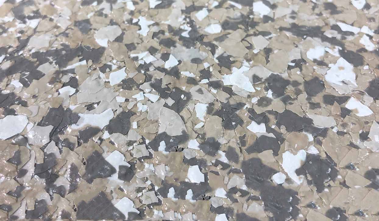 Close-up of a speckled floor coating, featuring a mix of gray, beige, and white flakes.