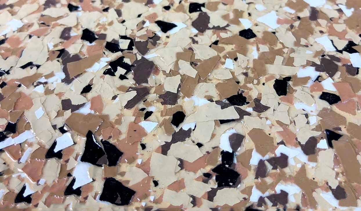 Close-up of a speckled, textured floor with light brown, black, white, and tan chips.