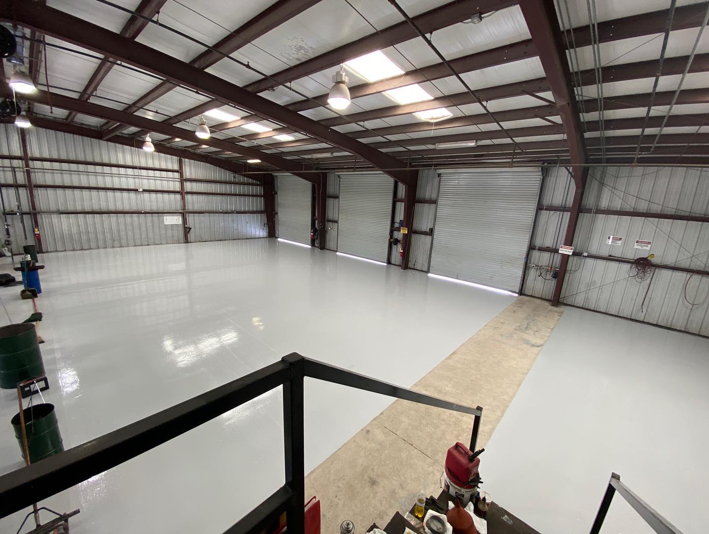 Warehouse interior with open garage doors and white floor.