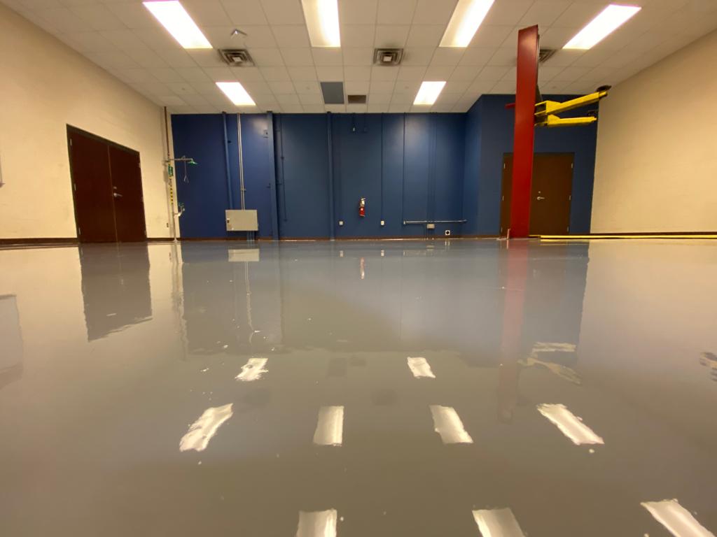 Empty room with reflective, gray floor and blue and beige walls; ceiling lights.