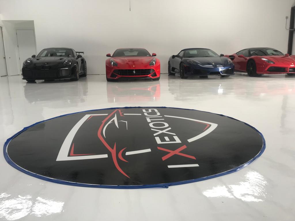 Four sports cars in a showroom, with a logo rug on the shiny floor.