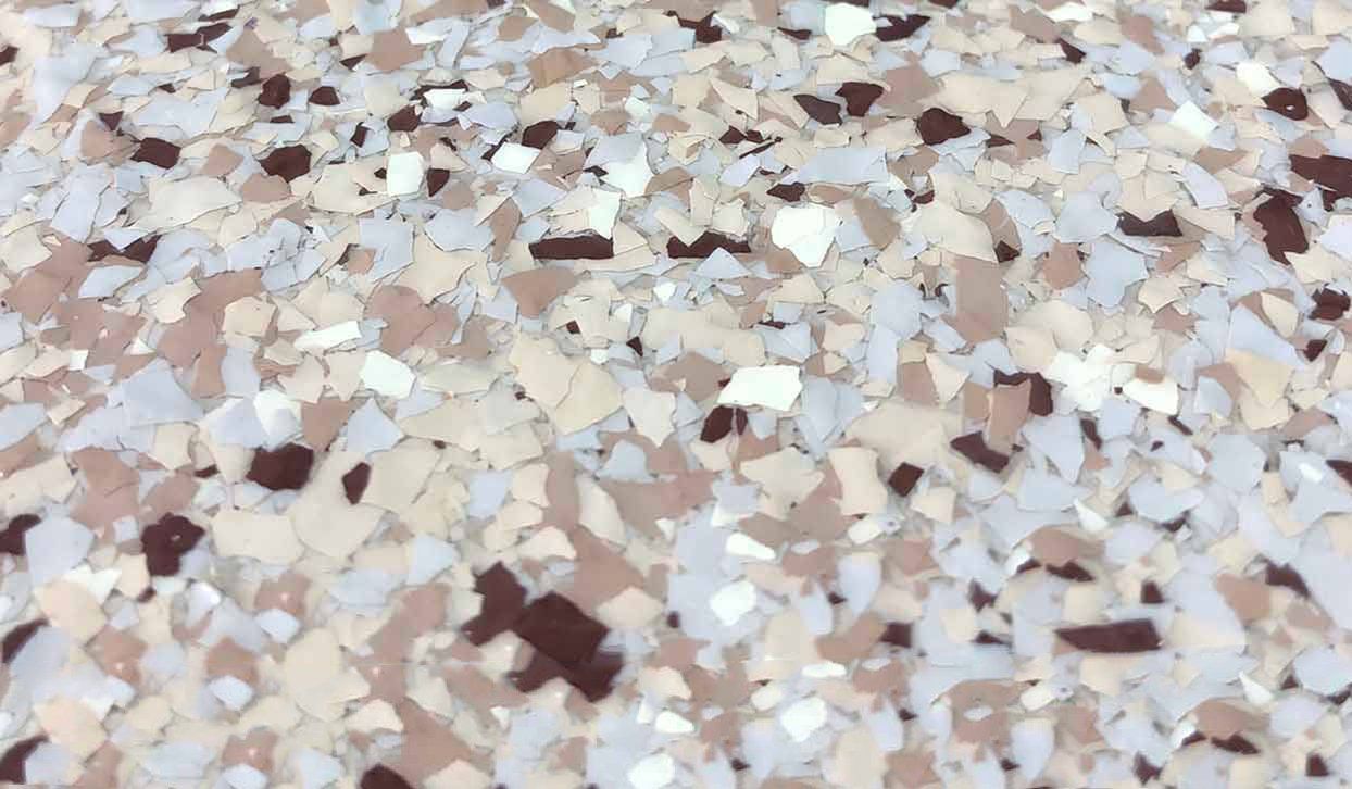 Close-up view of epoxy flooring with flecks of white, beige, brown, and gray.