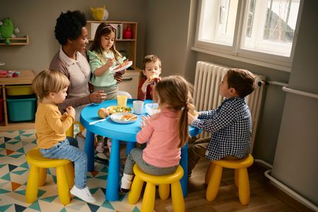 A group of children are sitting around a table eating food.