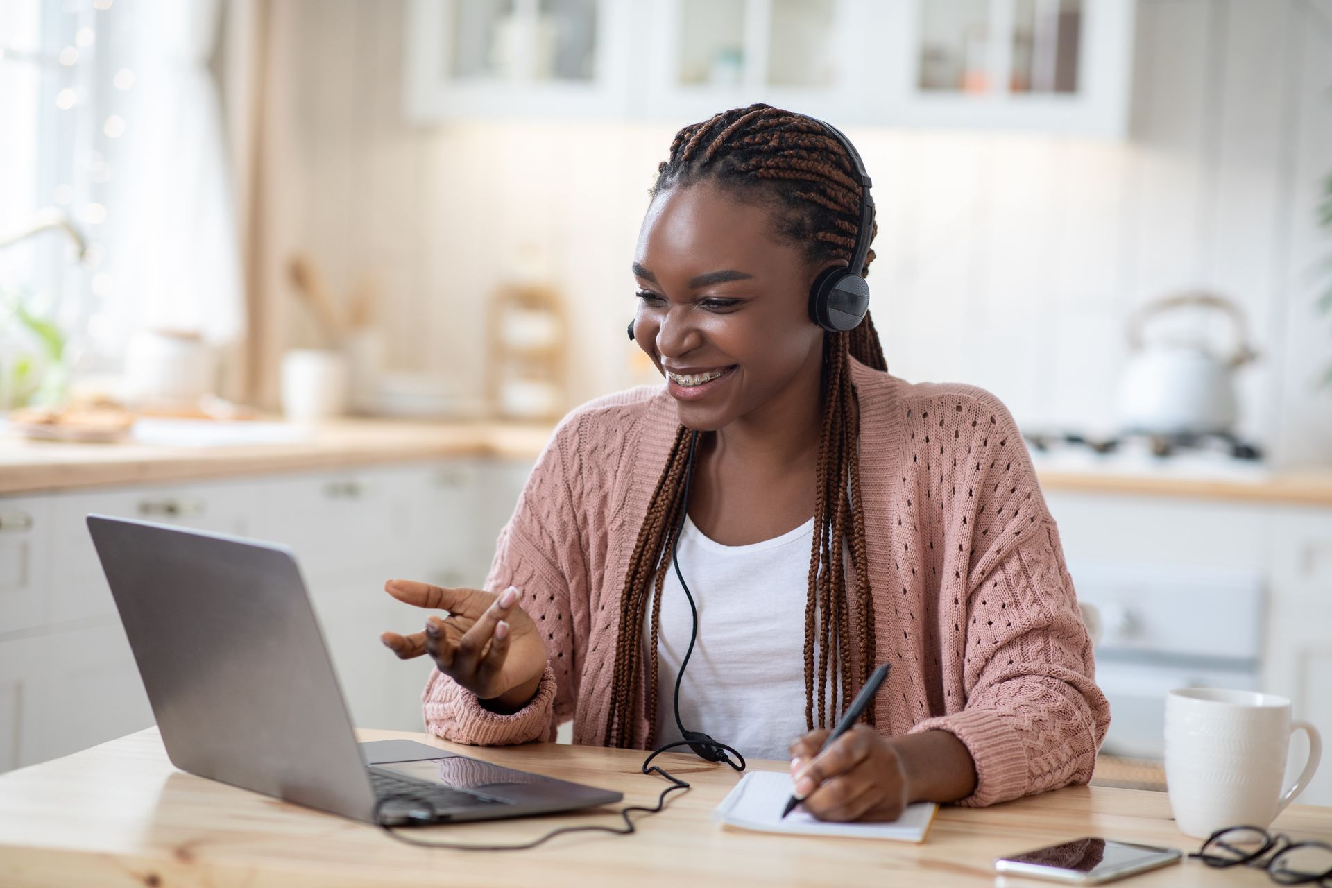 A woman is sitting at a table with a laptop and headphones on.