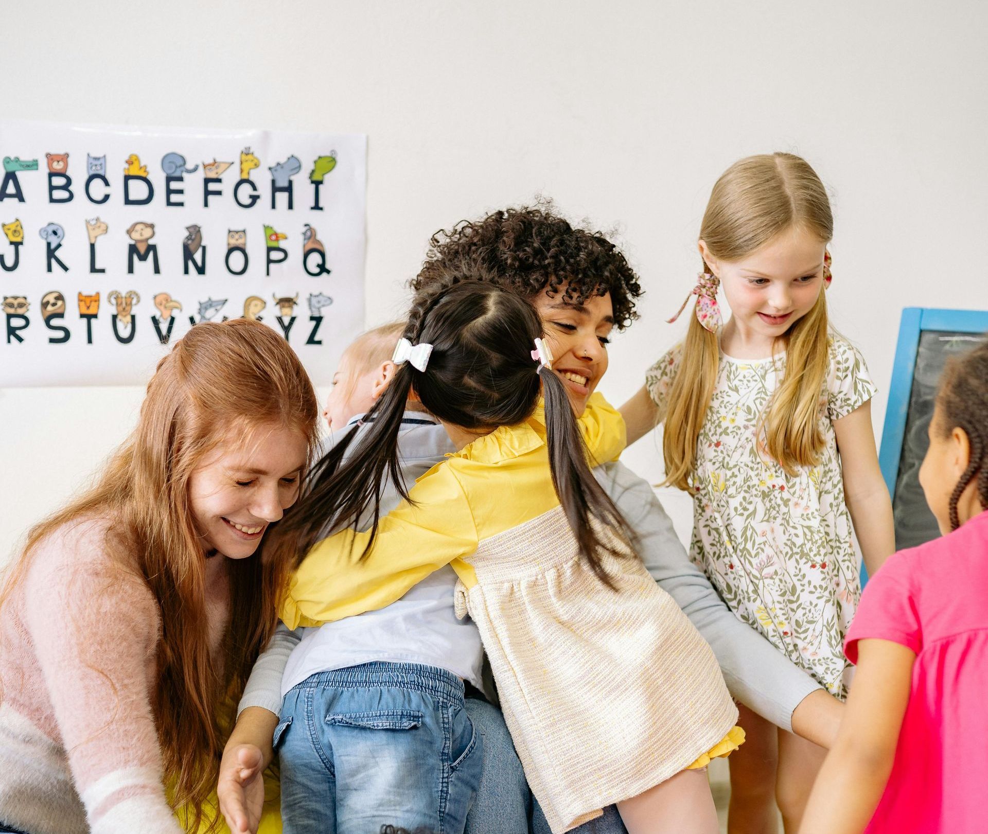 A group of children are hugging each other in a classroom.