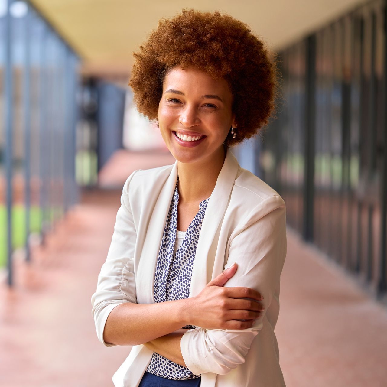 A woman with an afro is smiling with her arms crossed