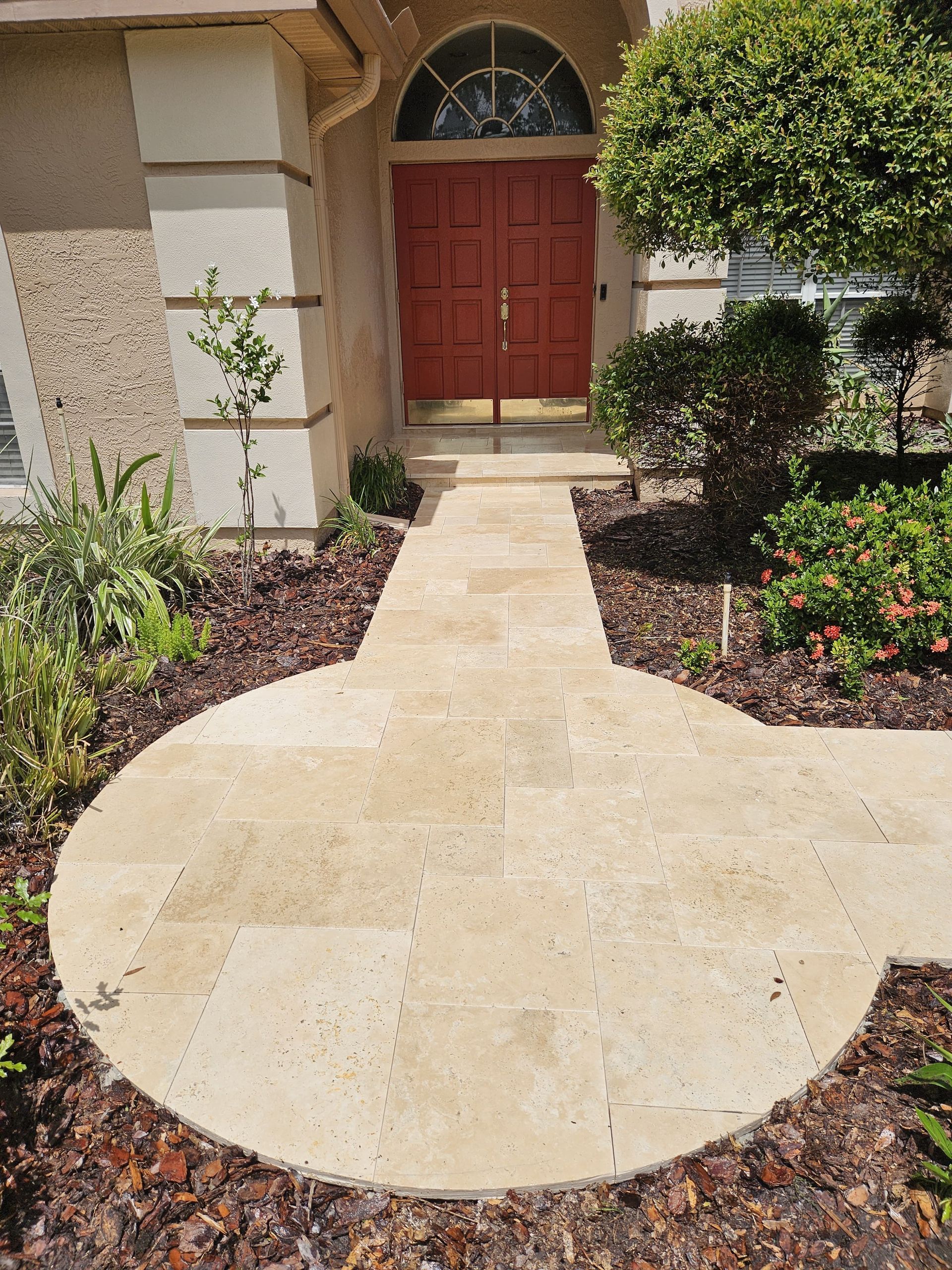 Stone paver driveway leading to a street, with a house in the background and a vehicle on the left.
