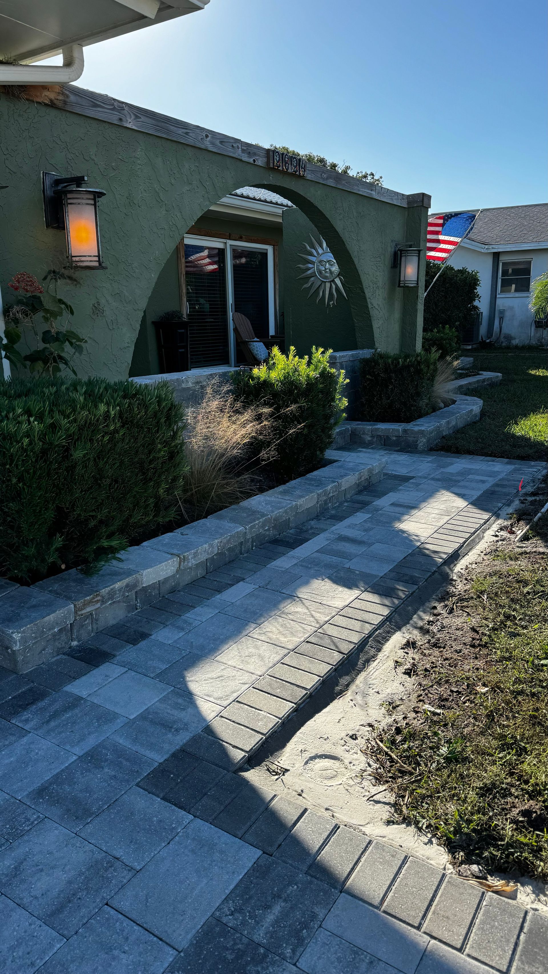 Exterior of a home with arched entrance, stone steps, and landscaping.