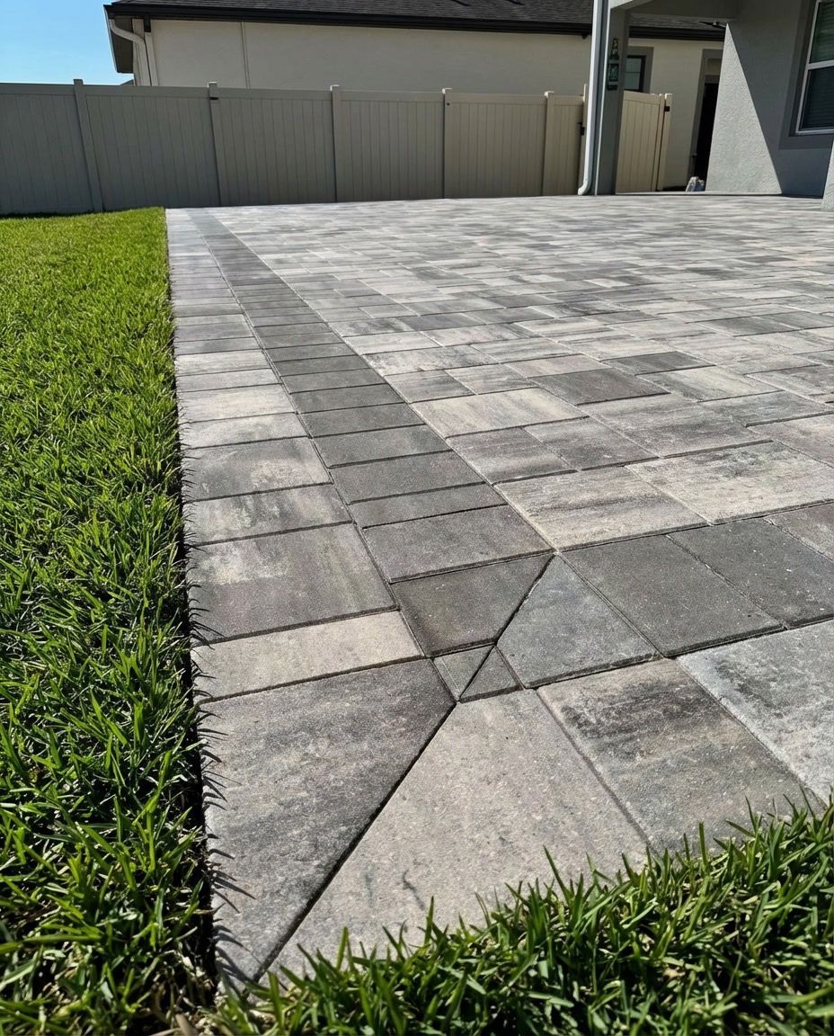 Beige stone walkway leading to a red double door entrance, surrounded by plants and mulch.