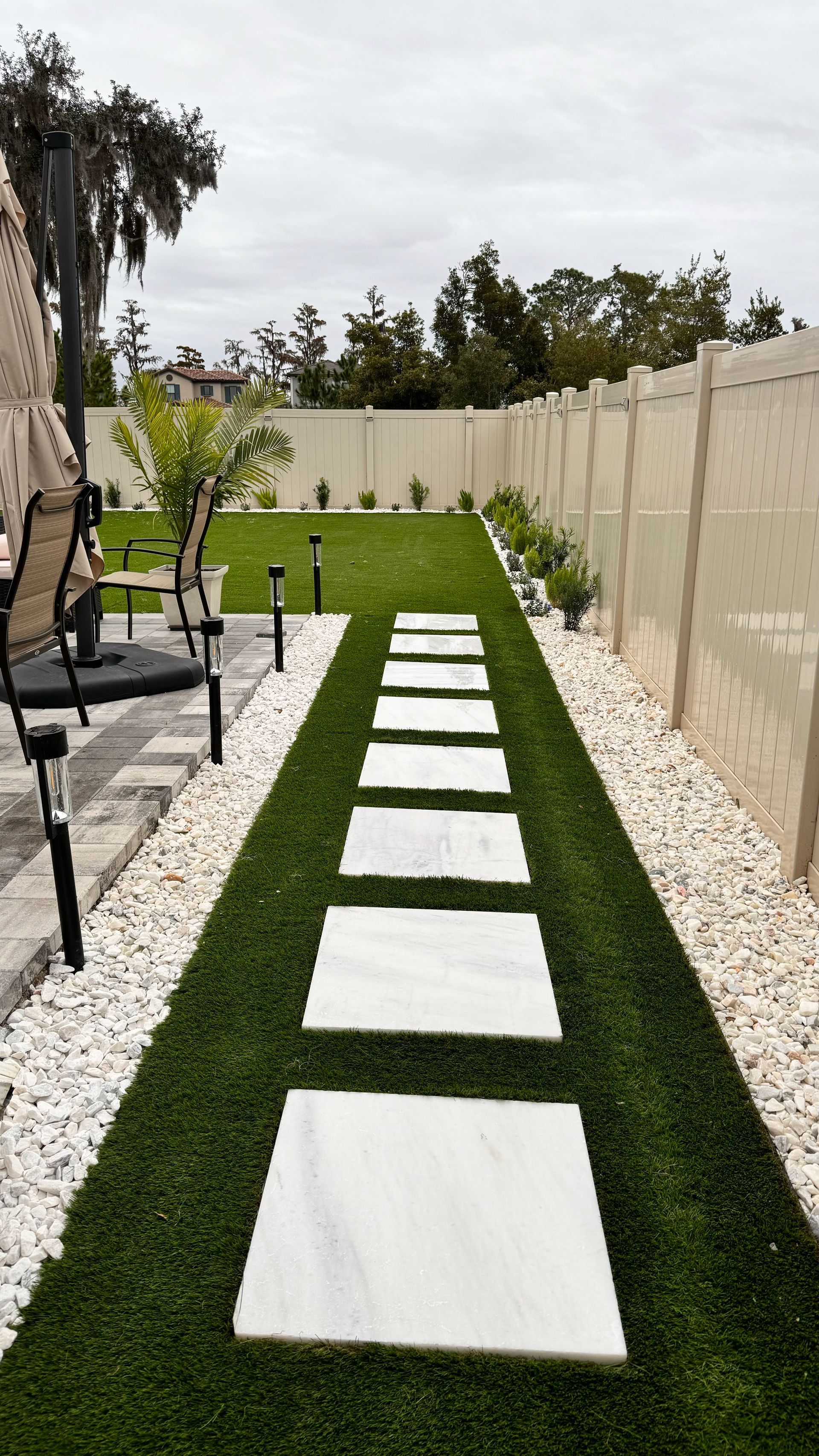 Stone patio with built-in curved seating and a central fire pit, surrounded by green grass and landscaping.