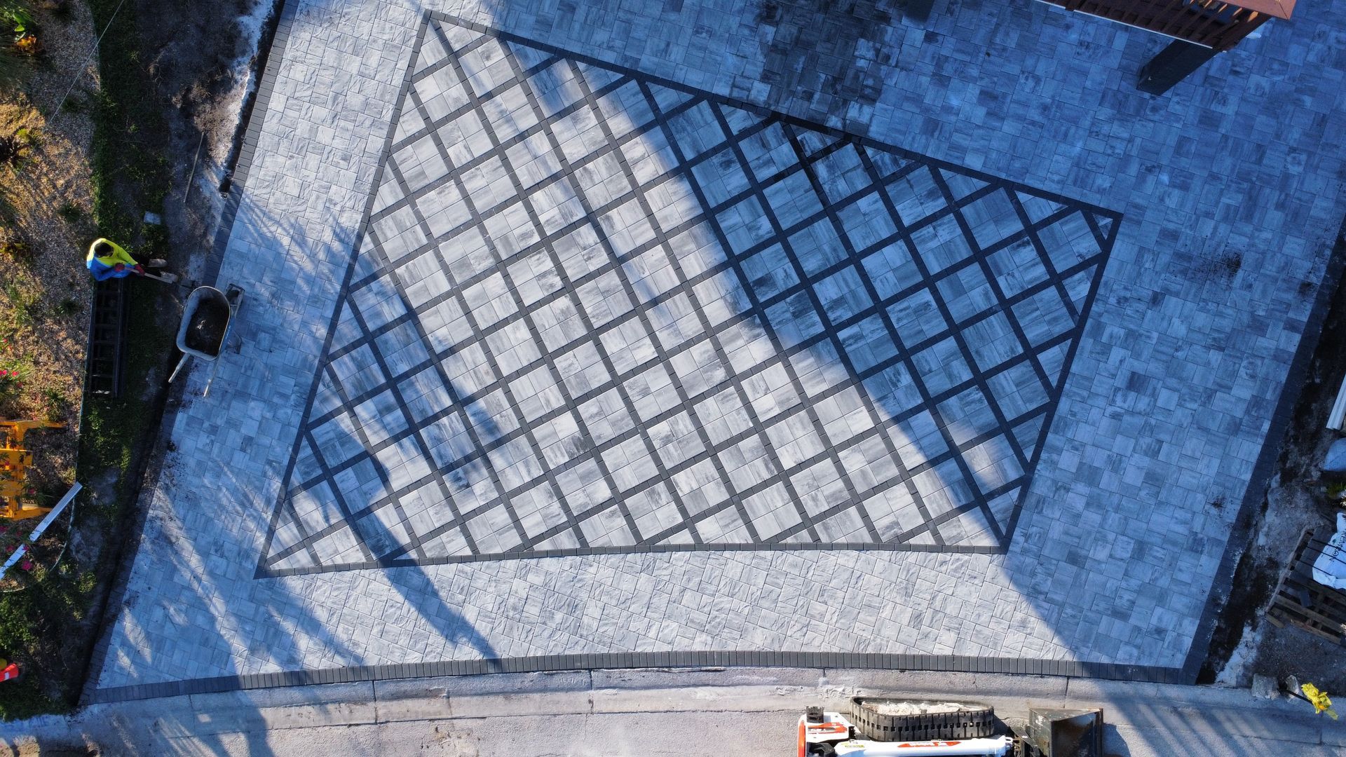 Aerial view of a paved patio with a diagonal grid pattern, surrounded by lighter paving stones.