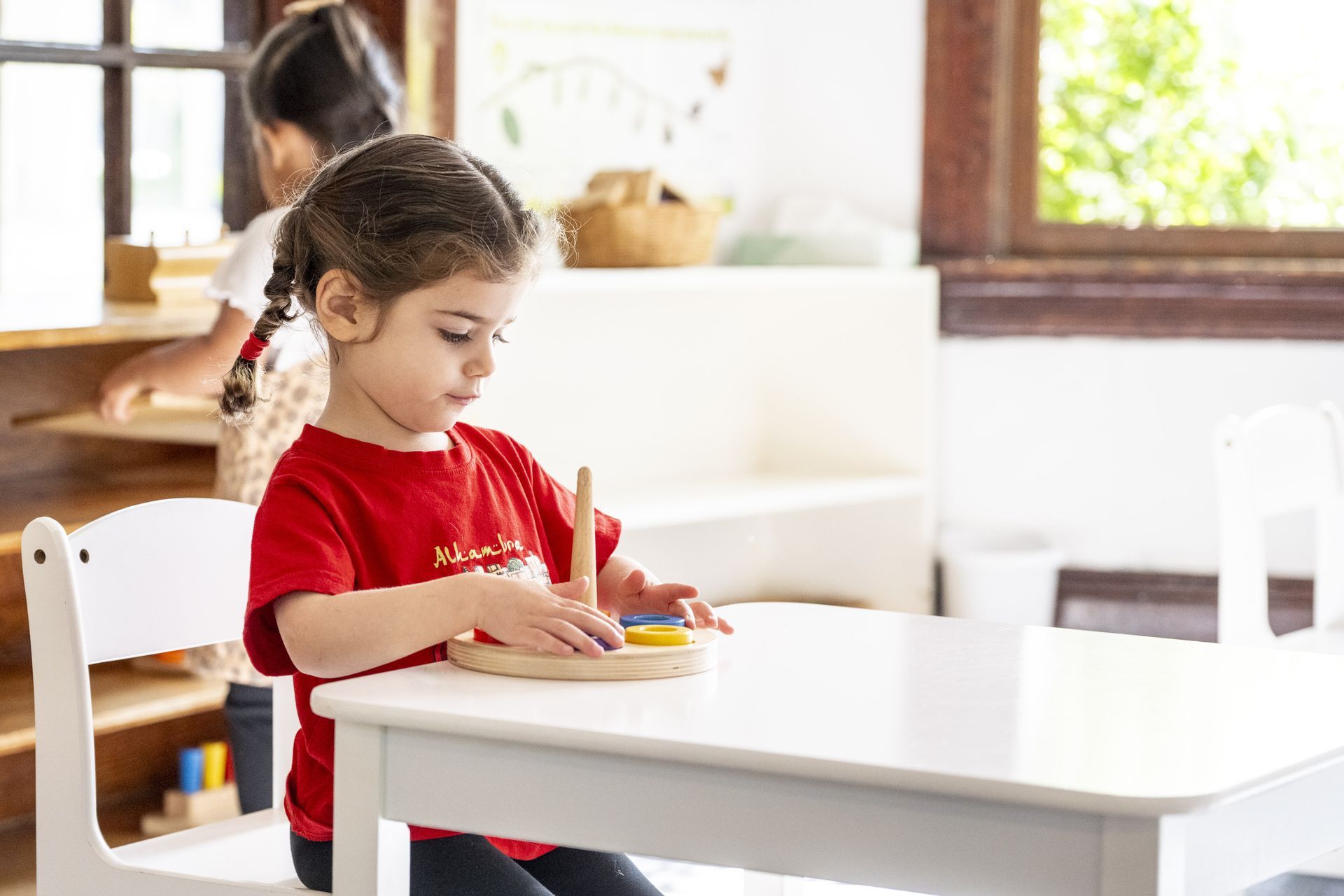 A Montessori child is sitting at a table working with a wooden toy.