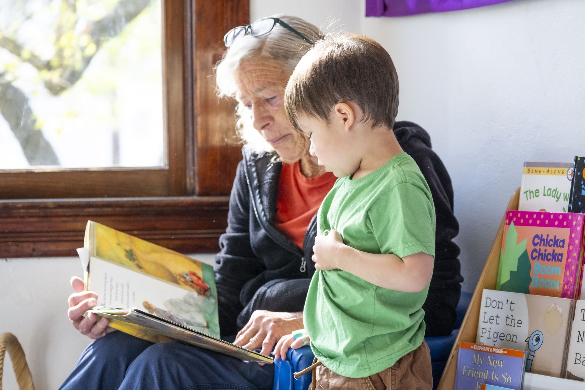 A Montessori guide is reading a book to a child