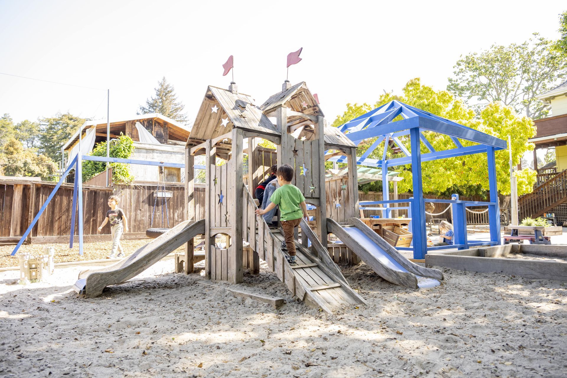 Montessori children are playing on a wooden playground set.