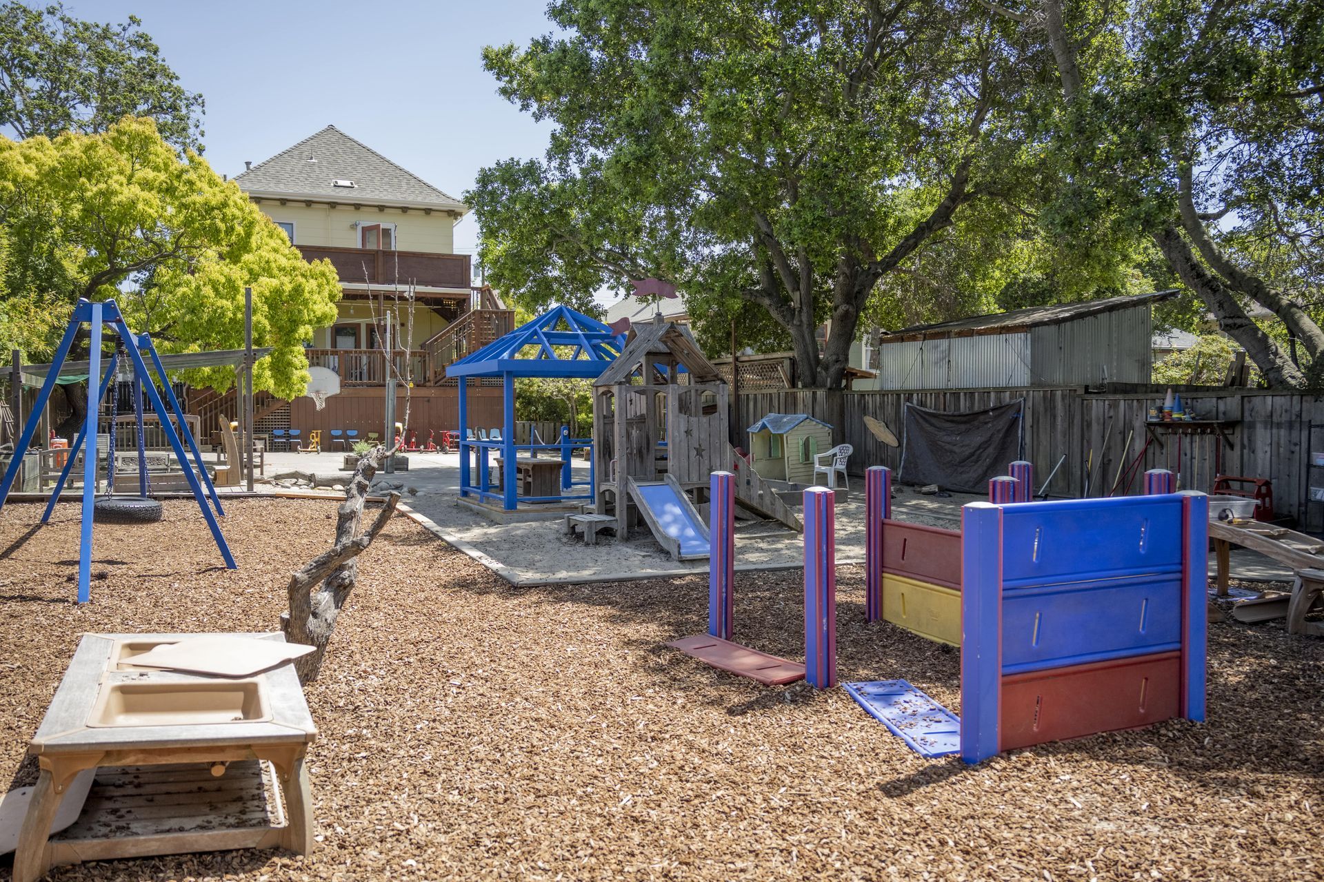 A playground with a blue house in the middle of it.