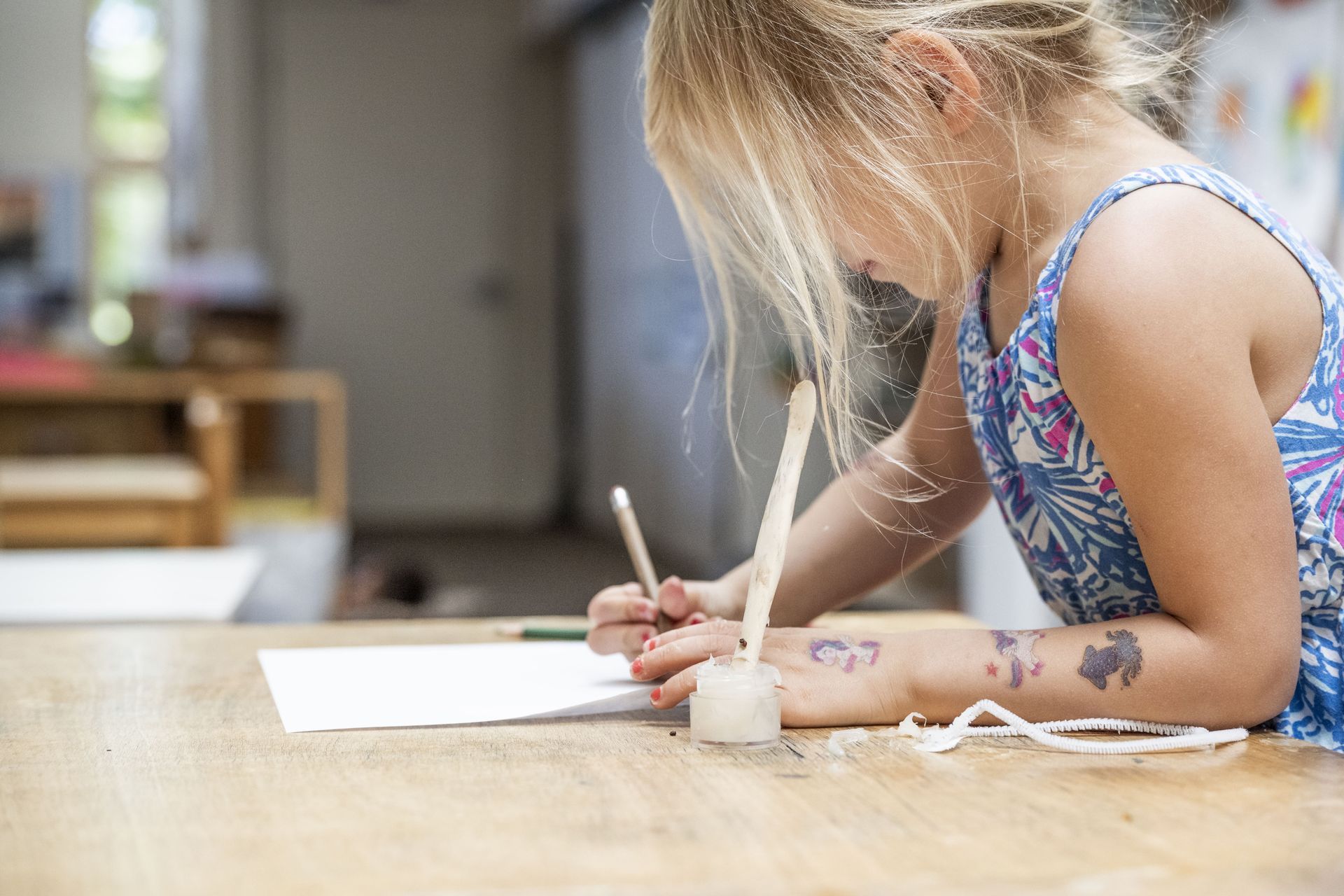A Montessori child is sitting at a table writing on a piece of paper.