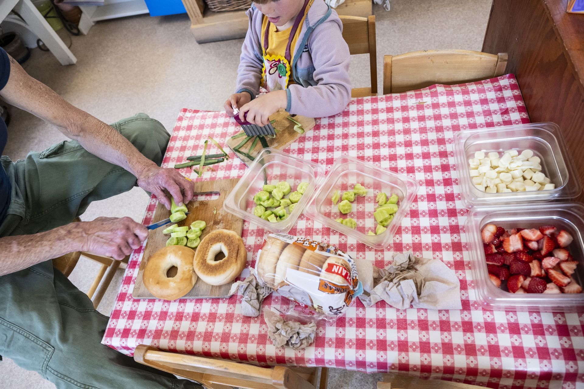 A Montessori guide and child are sitting at a table with food on it.