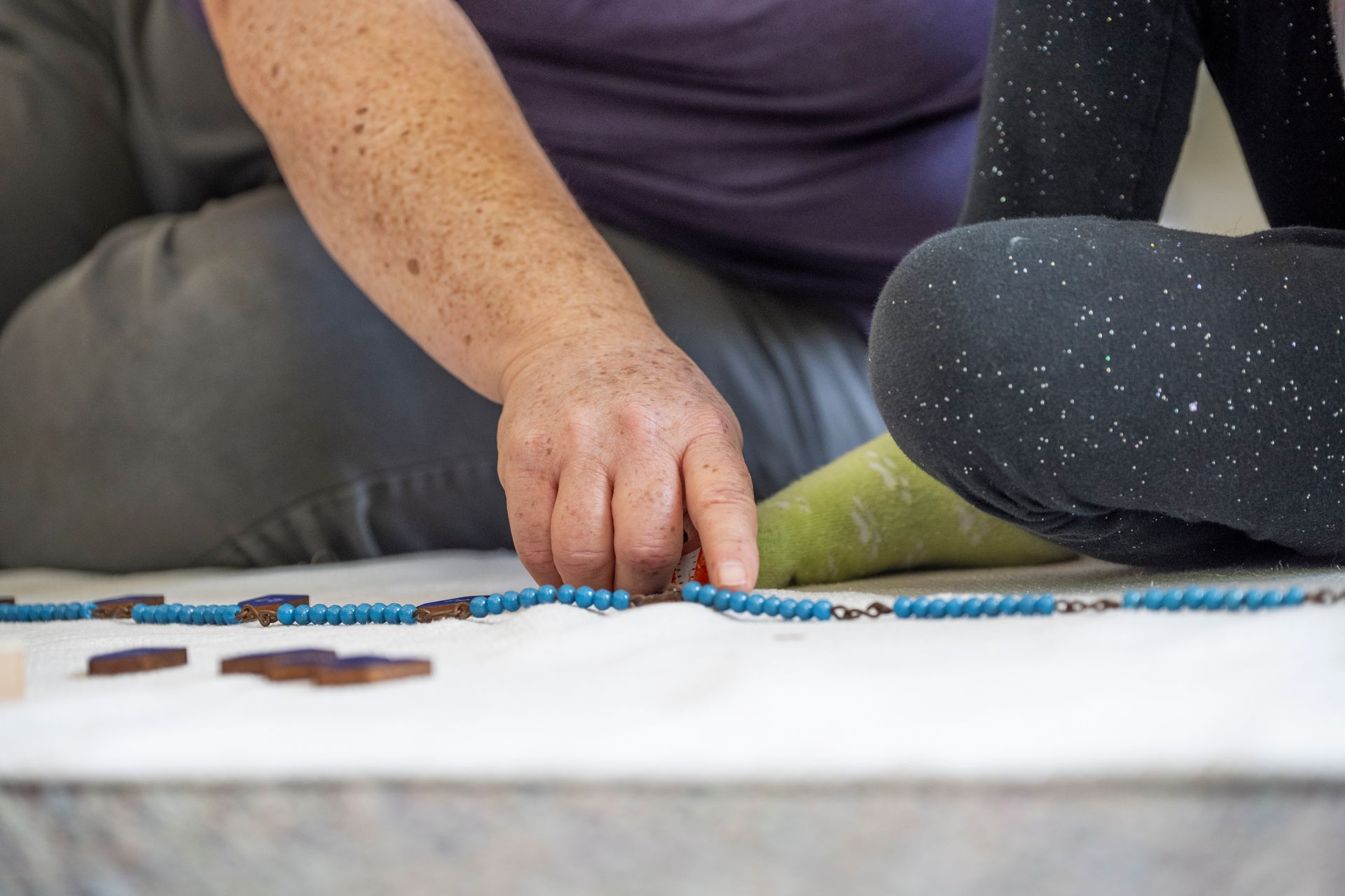 A Montessori guide and a child are working with math beads