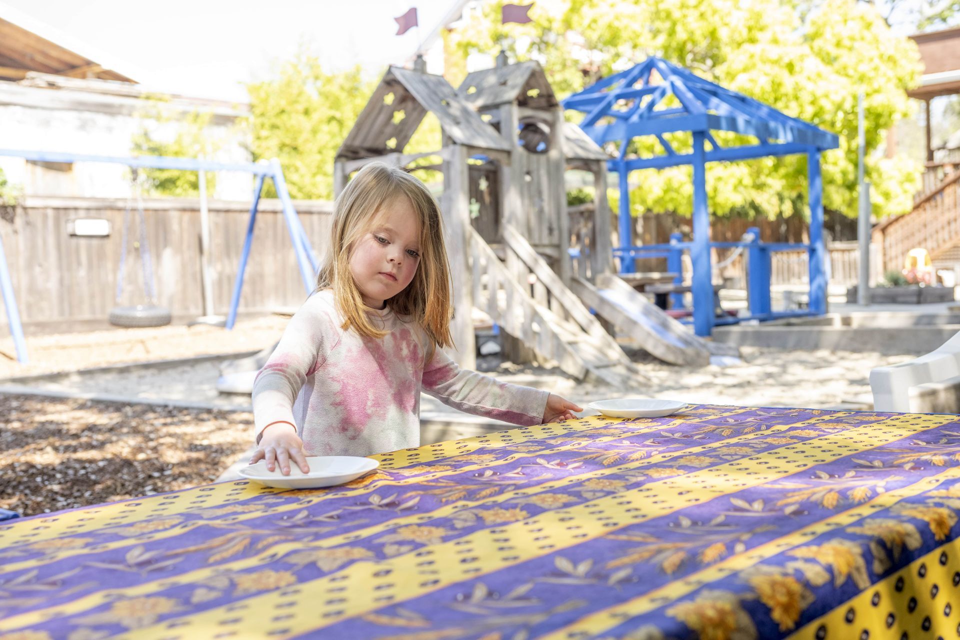 A Montessori child is sitting at a table in front of a playground.