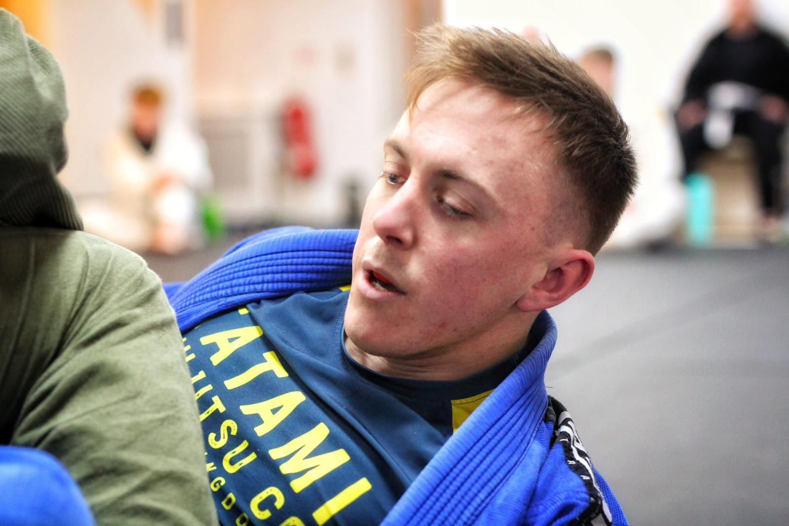 Athlete in blue gi lying on mats during a grappling match