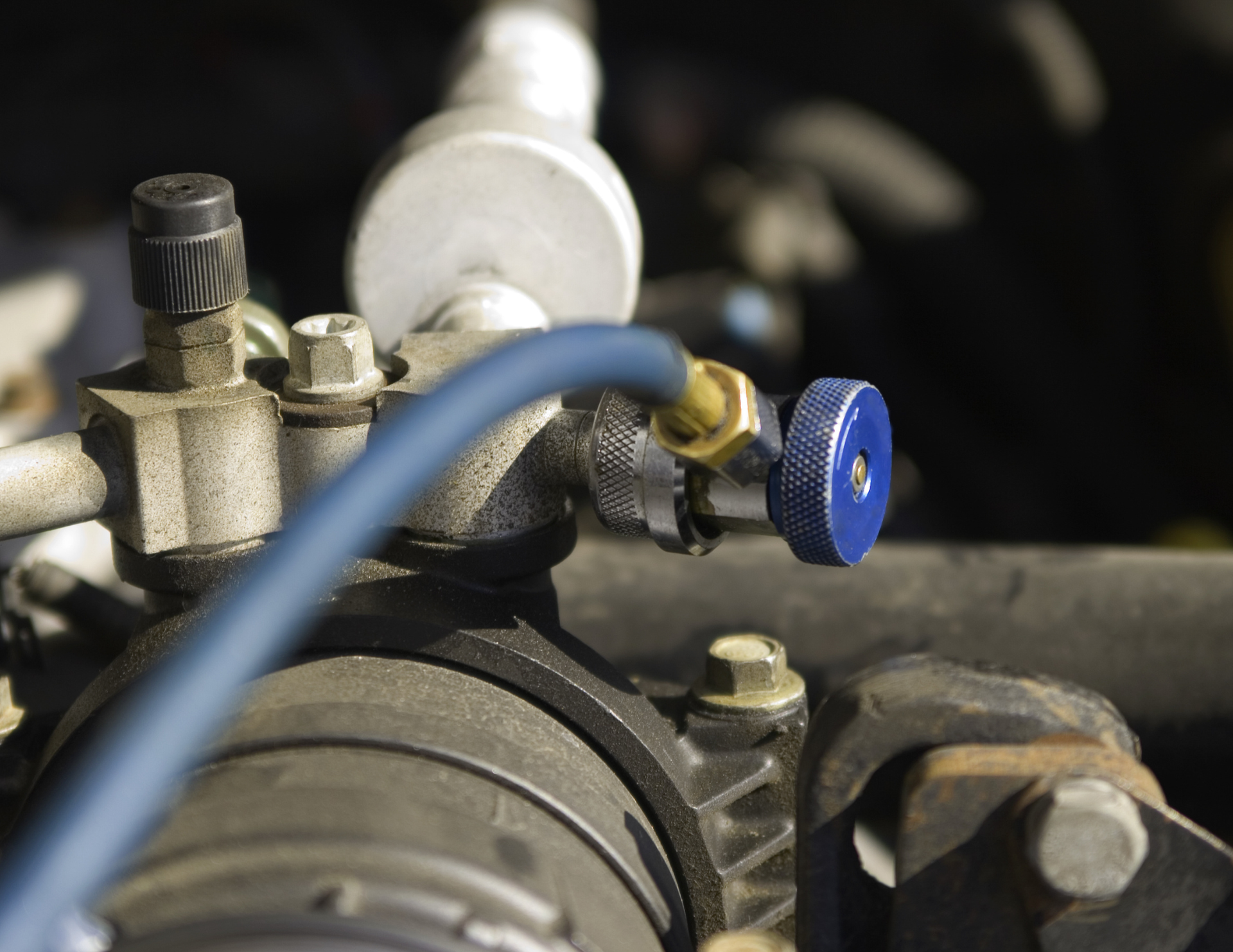 Close-up of car AC components with a blue valve attached.