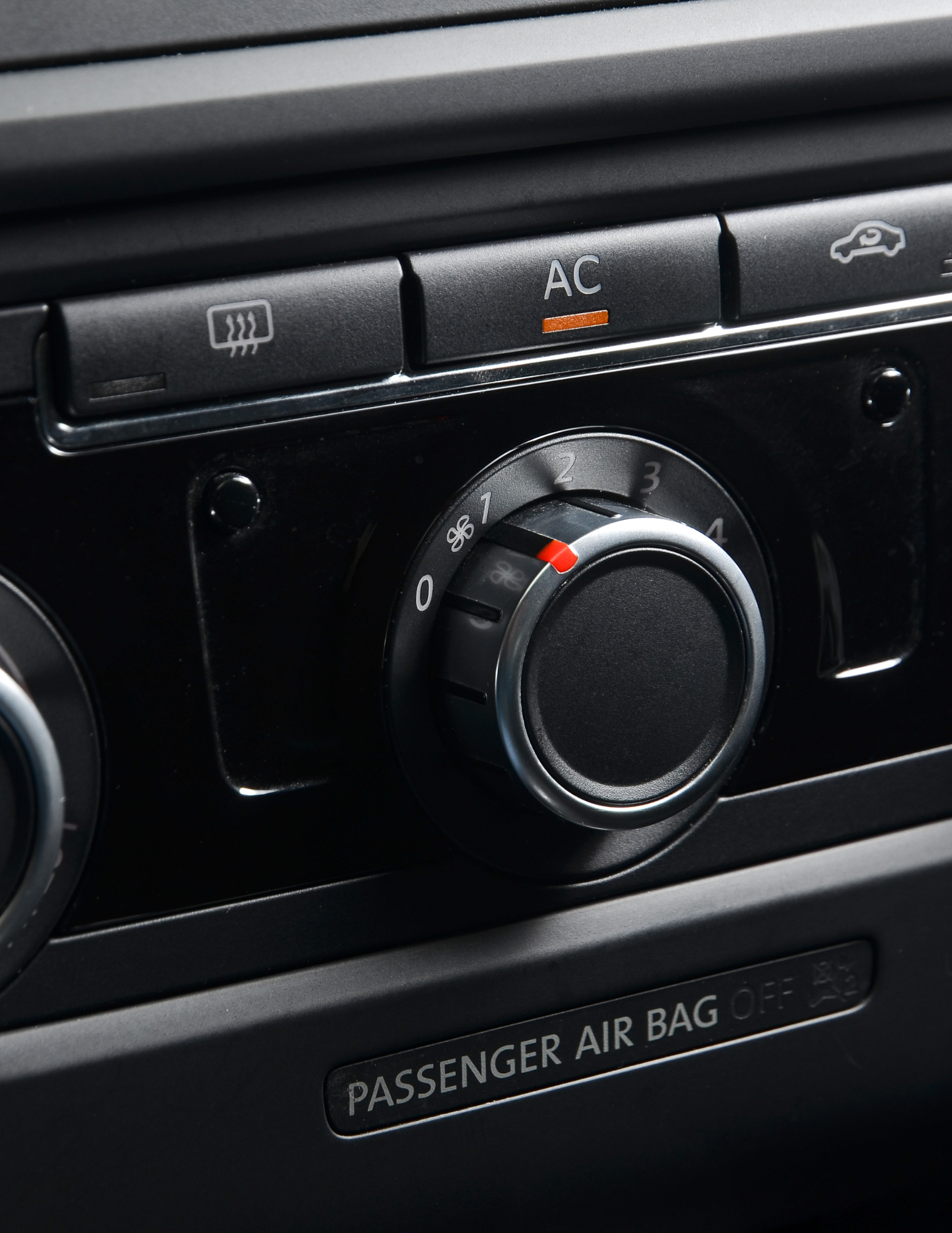 Car dashboard with climate control knobs and air bag indicator.