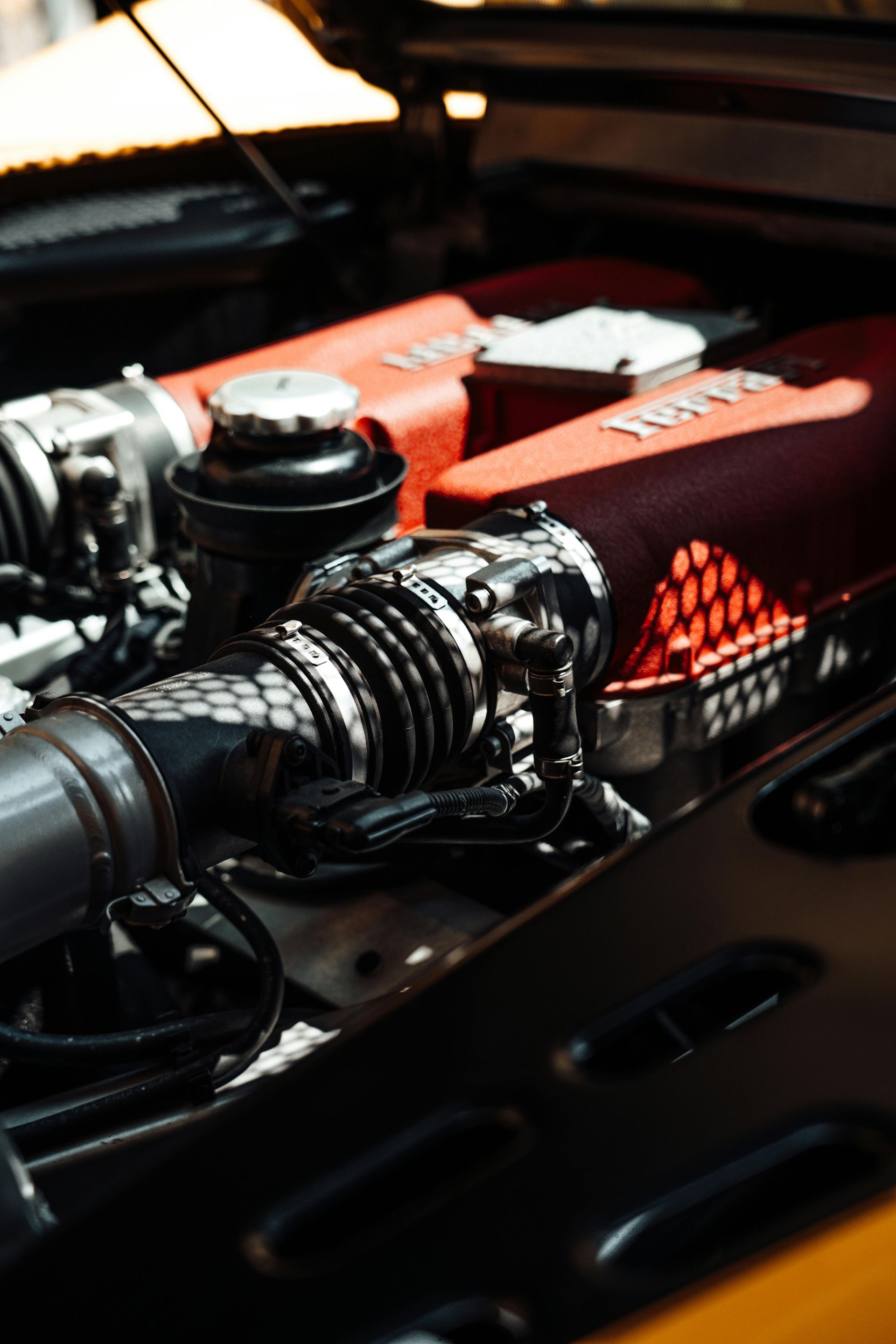 Ferrari engine with red valve covers and chrome air intake.