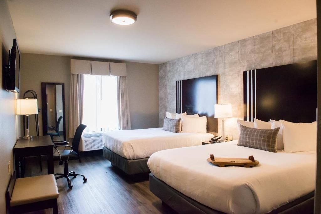 Hotel room with two queen beds, desk, and window with daylight