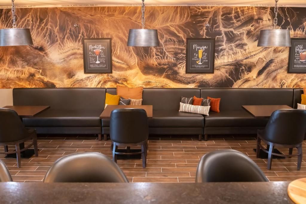 Cozy lounge with black leather sofas, pendant lights, framed art, and warm wood-and-stone decor.
