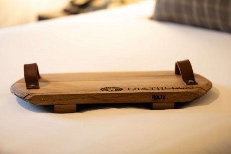 Wooden stand with two brown straps on a white surface, shown in close-up.