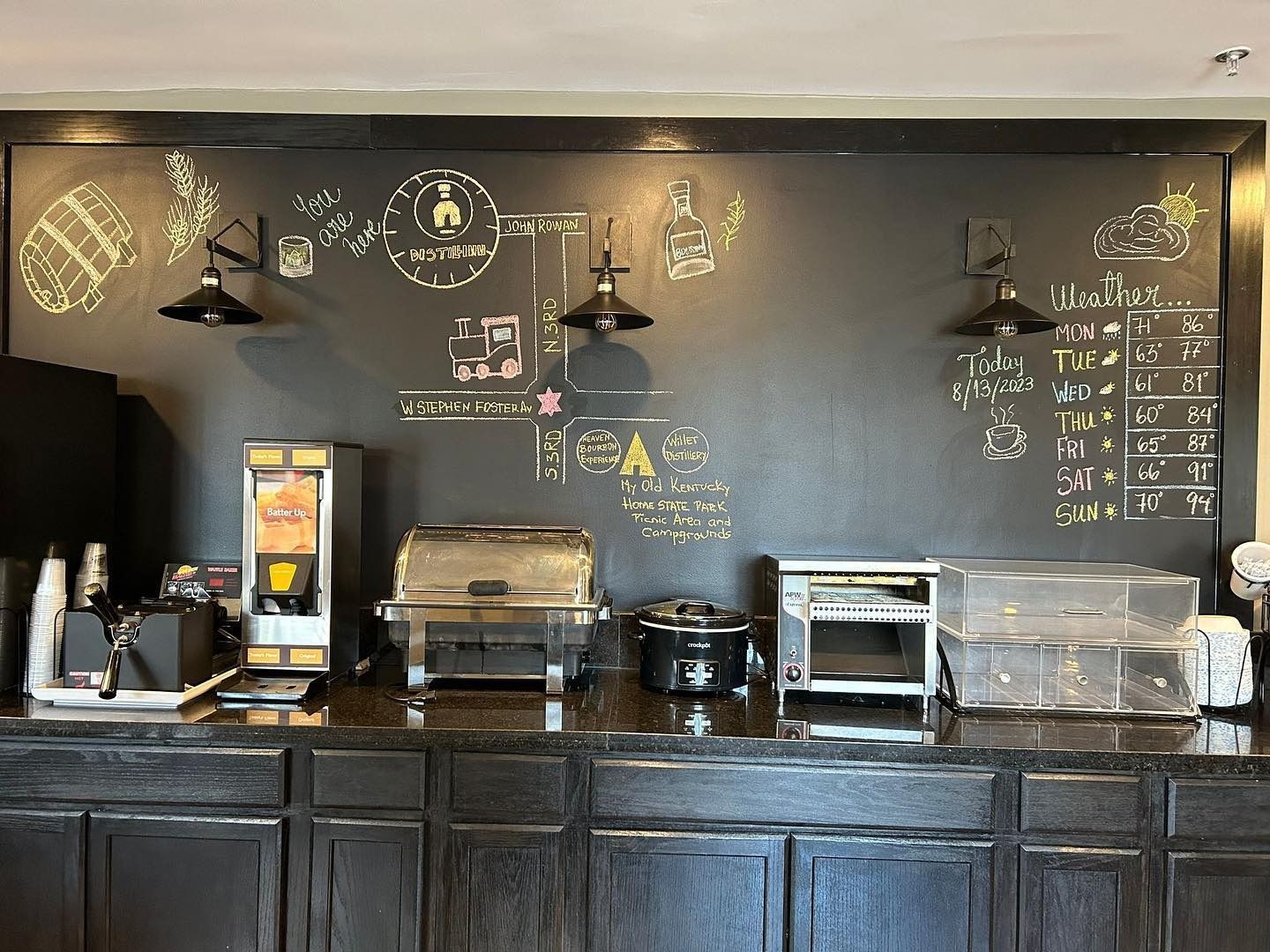 Modern café counter with espresso machines, menu boards, and pastries behind a dark wood bar