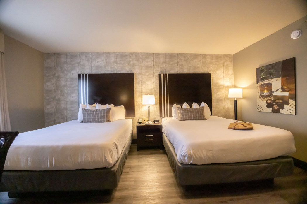 Hotel room with two queen beds, bedside lamps, and warm neutral decor