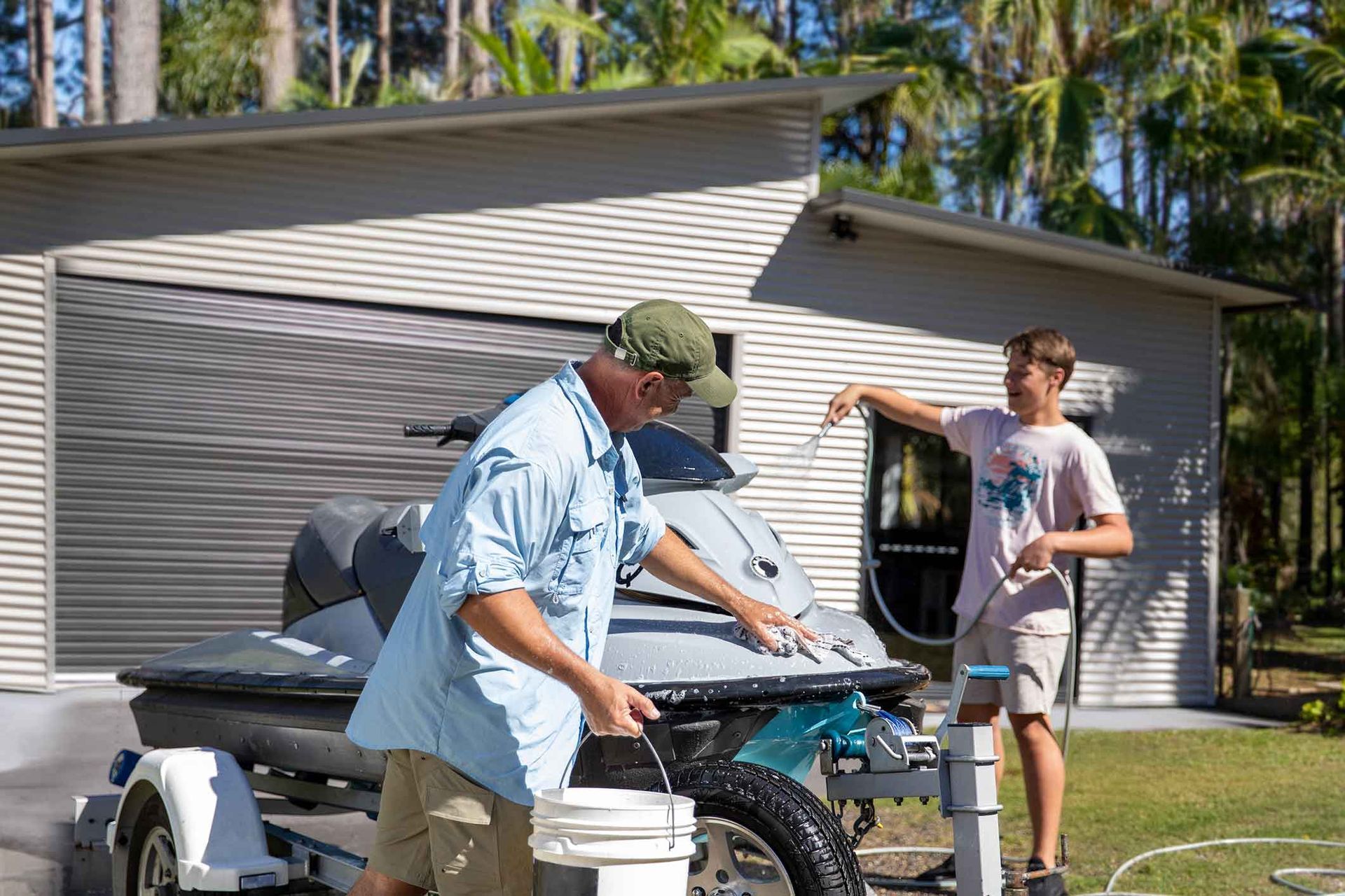 A Man And A Boy Are Washing A Jet Ski In Front Of A Shed – South Kempsey NSW - Fair Dinkum Builds Macleay Valley Sheds