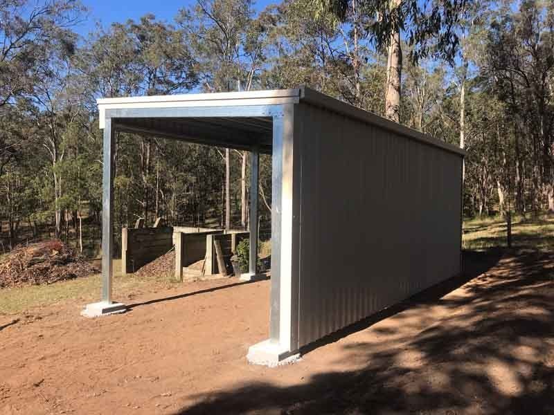 A Metal Shed Is Sitting On Top Of A Dirt Field In The Middle Of A Forest