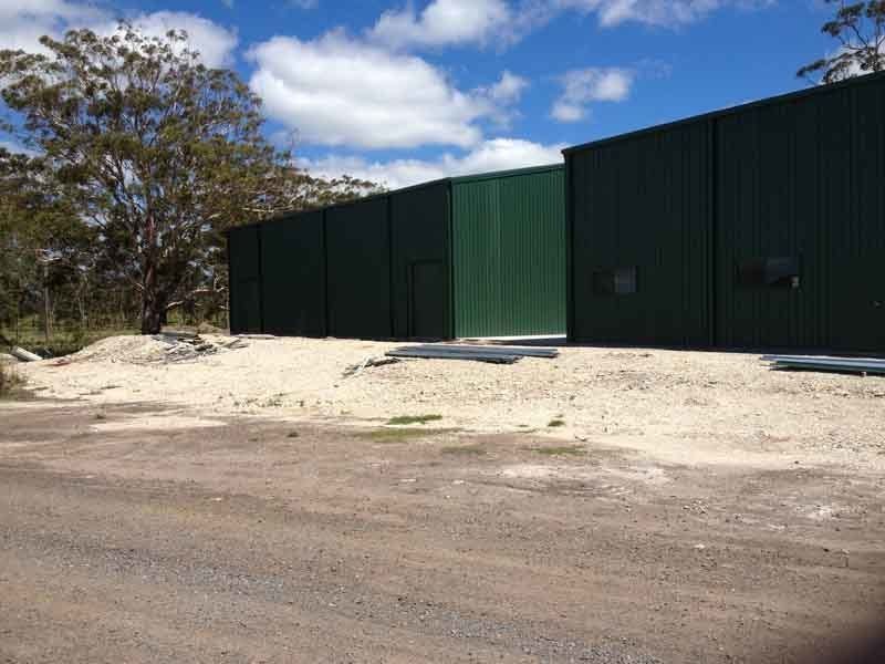 A Large Green Warehouse Sheds Are Sitting In The Middle Of A Dirt Field