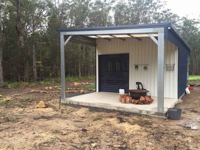 A Small Building With A Covered Porch And A Fire Pit In Front Of It