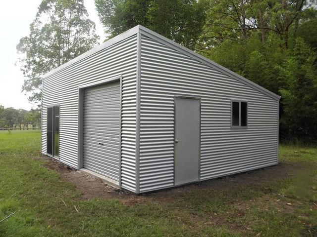 A Small Metal Building Is Sitting In The Middle Of A Grassy Field 
