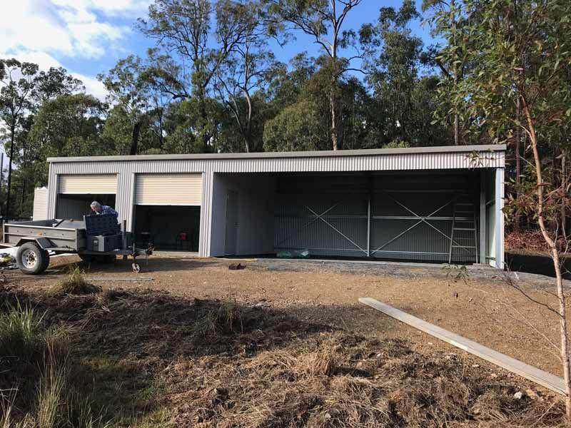 A Large Metal Building With A Trailer Parked In Front Of It – South Kempsey NSW - Fair Dinkum Builds Macleay Valley Sheds