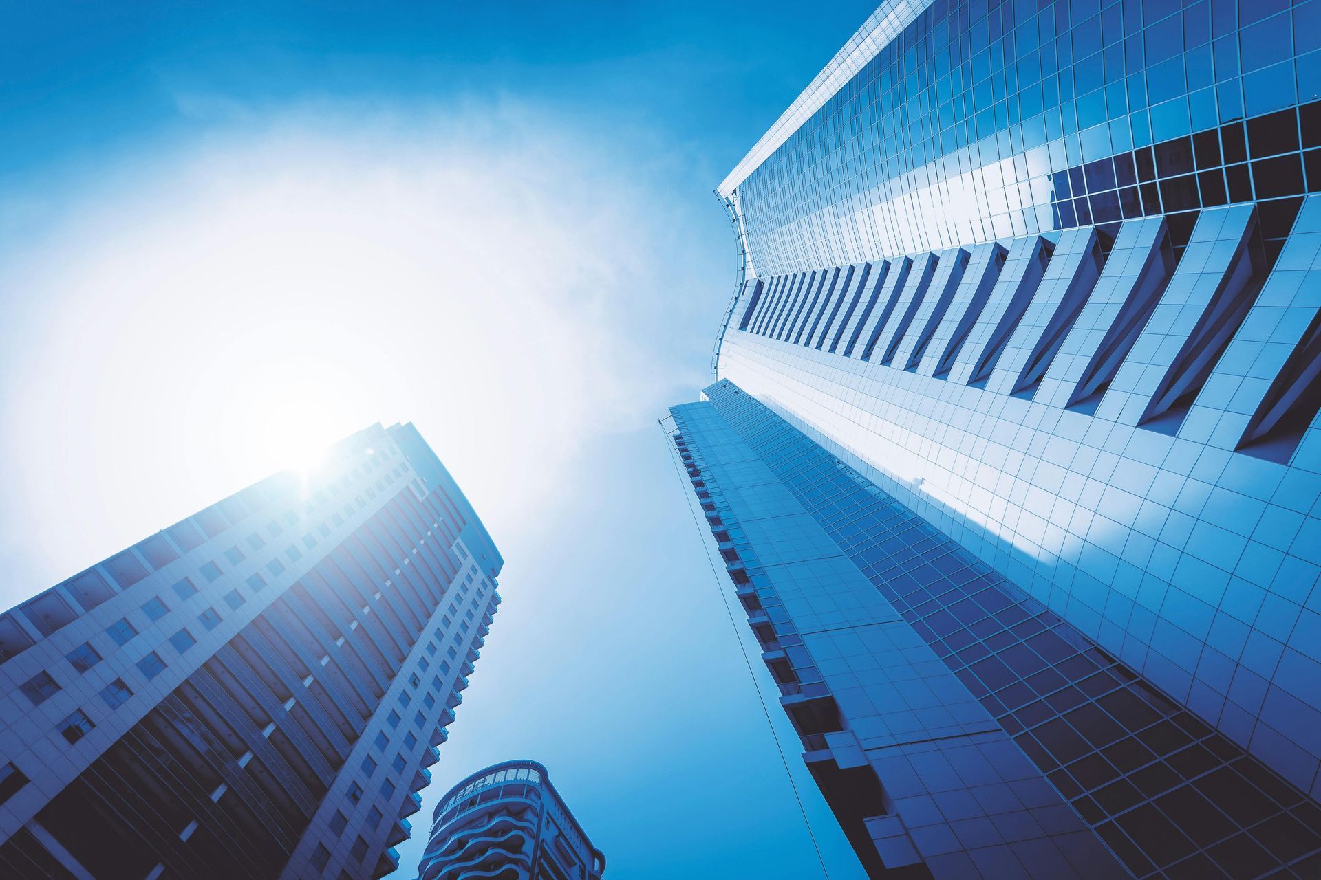 Blue skyscrapers viewed from below against a bright sky