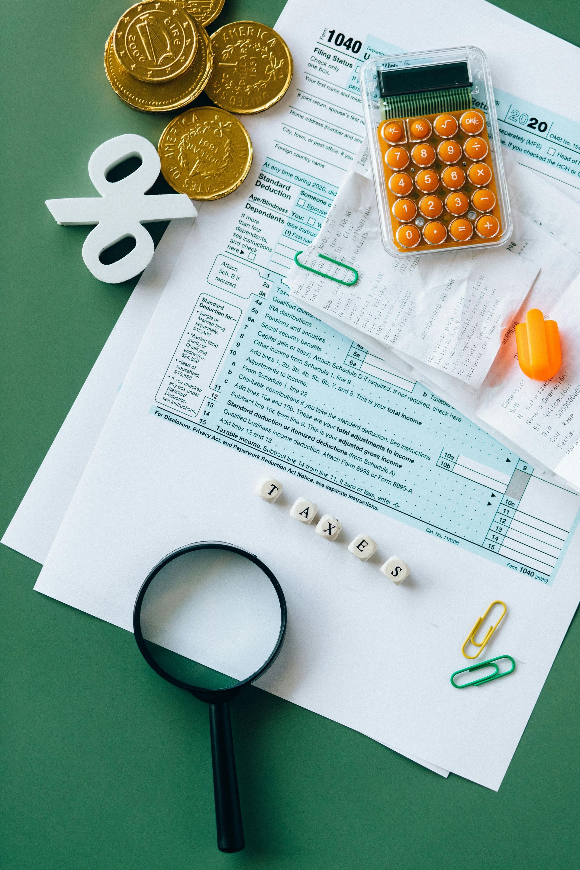 Pills, coins, magnifying glass, and papers on a green desk, suggesting healthcare costs or prescription billing