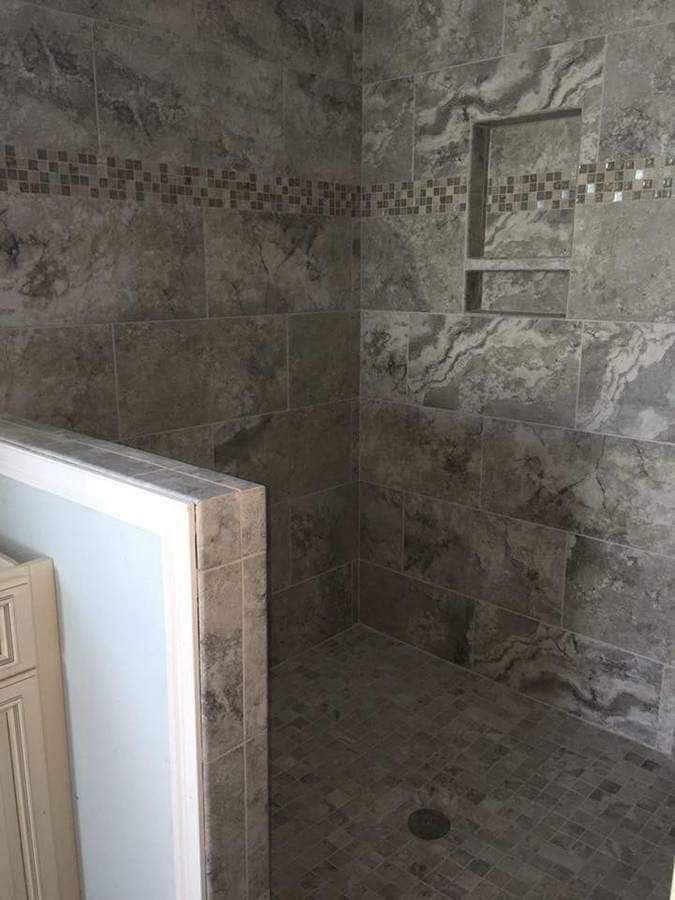 A bathroom with a walk in shower and a shelf in the wall.
