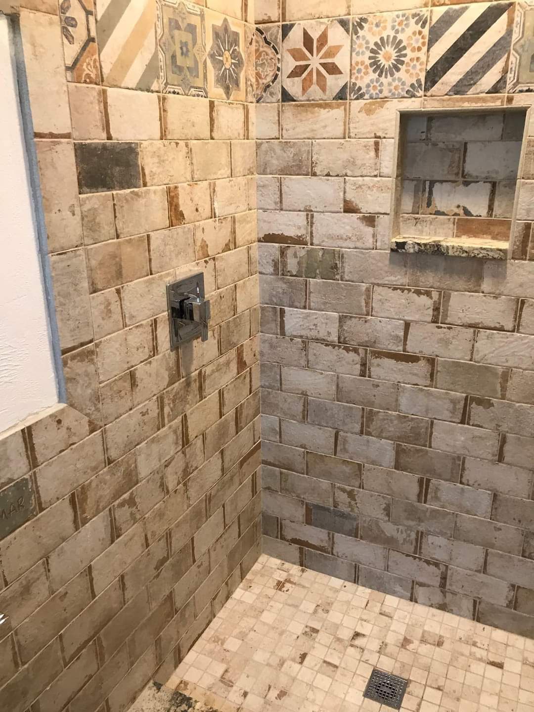 A shower with a brick wall and a tiled floor.