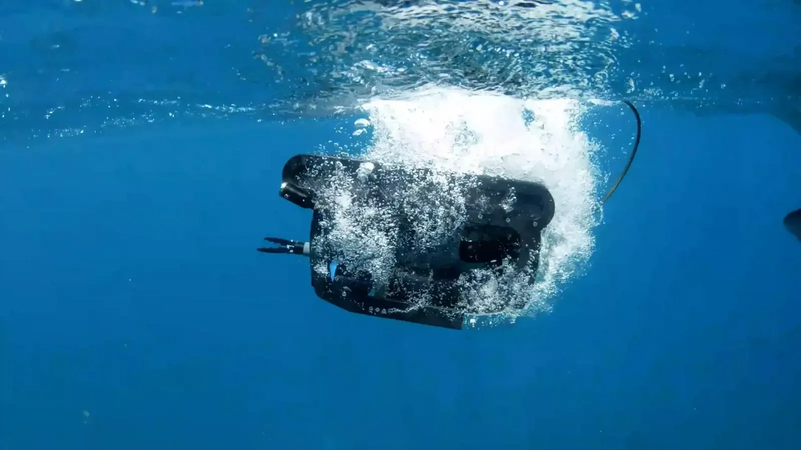 Black underwater device or camera splashing in clear blue water