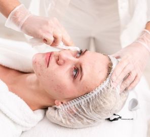 Facial spa treatment with a woman wearing a hair cap while a technician applies cream to her face