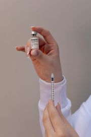 Hands holding a vial and a syringe, preparing a vaccine injection